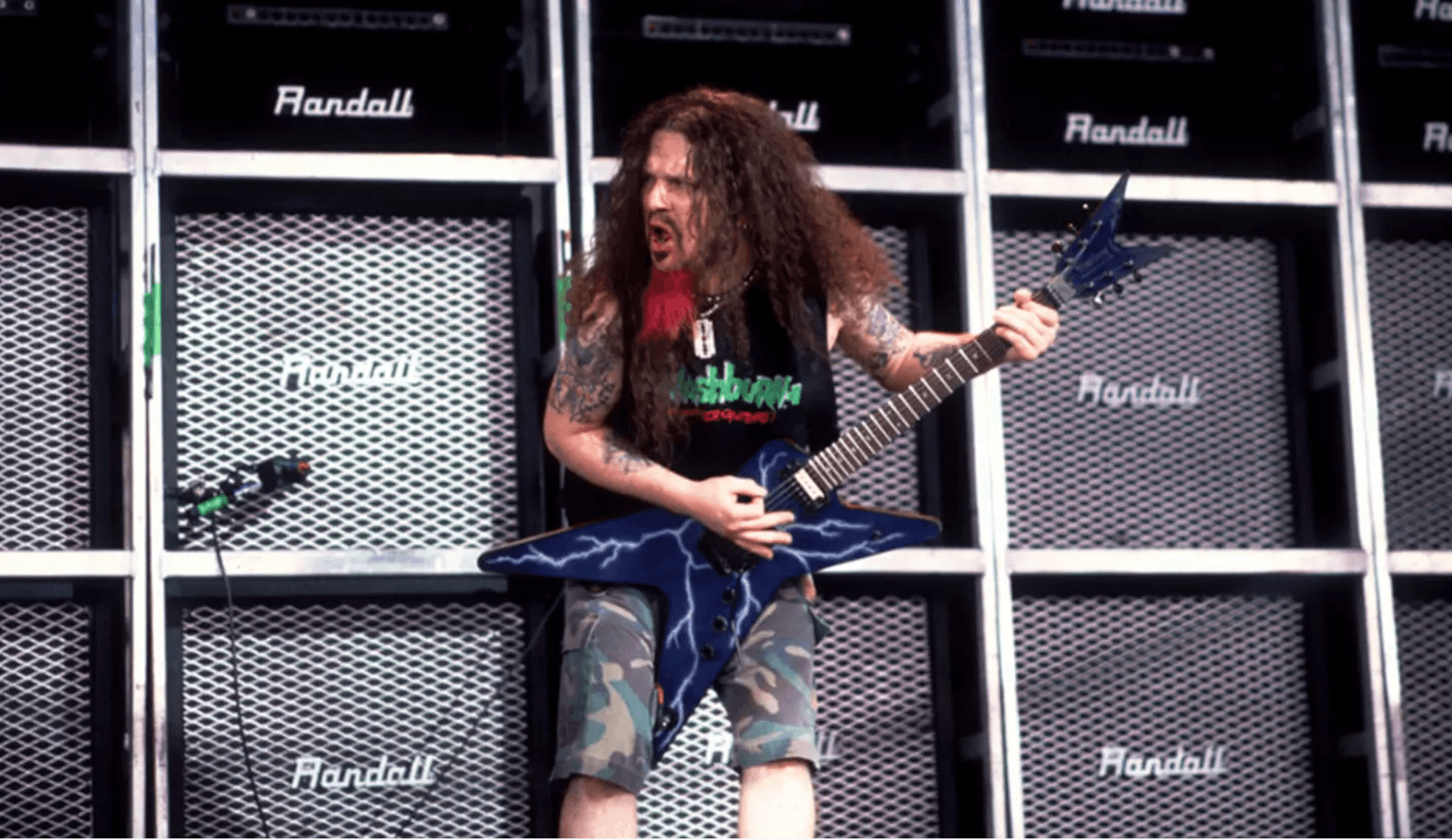 Dimebag Darrell playing guitar in front of a wall of Randall amplifiers